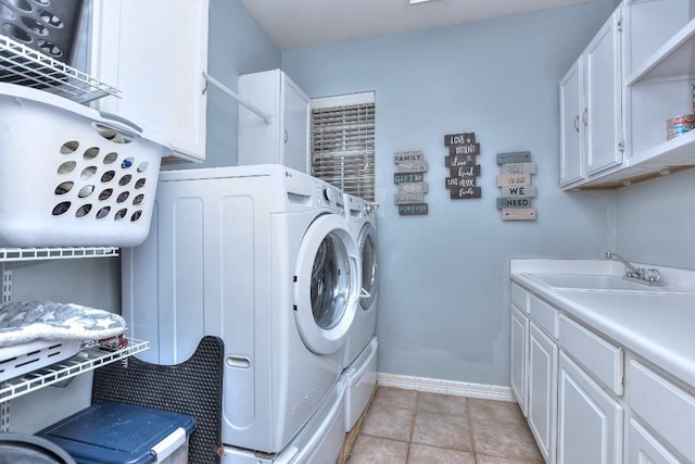 laundry area featuring baseboards, washing machine and clothes dryer, light tile patterned flooring, cabinet space, and a sink