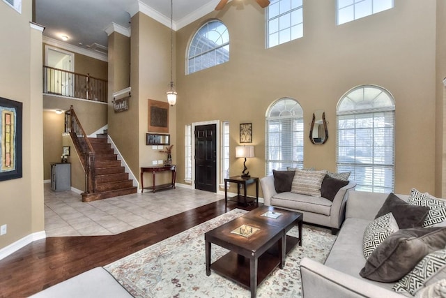 living area with stairs, crown molding, wood finished floors, and a healthy amount of sunlight