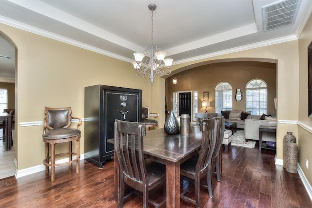 dining room featuring visible vents, a notable chandelier, wood finished floors, arched walkways, and a raised ceiling