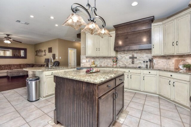 kitchen featuring visible vents, custom range hood, light tile patterned floors, a peninsula, and a sink