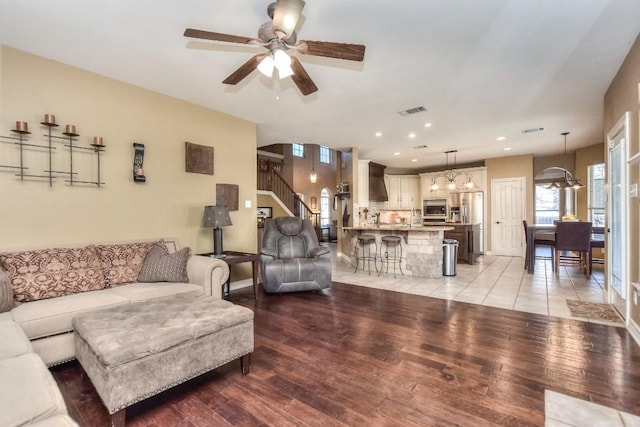 living area featuring visible vents, stairway, recessed lighting, ceiling fan with notable chandelier, and light wood-style floors