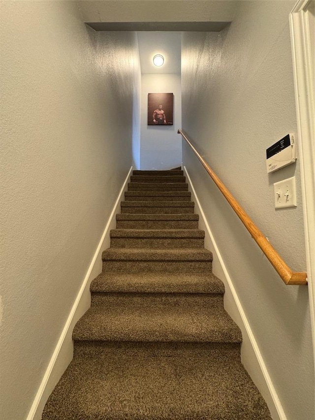 stairway with baseboards, carpet floors, and a textured wall