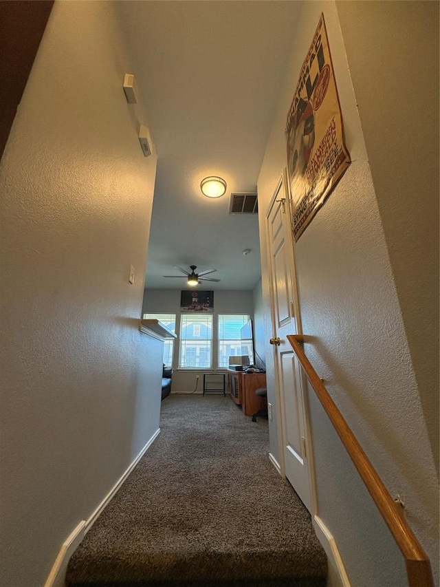 hallway with carpet, visible vents, and baseboards