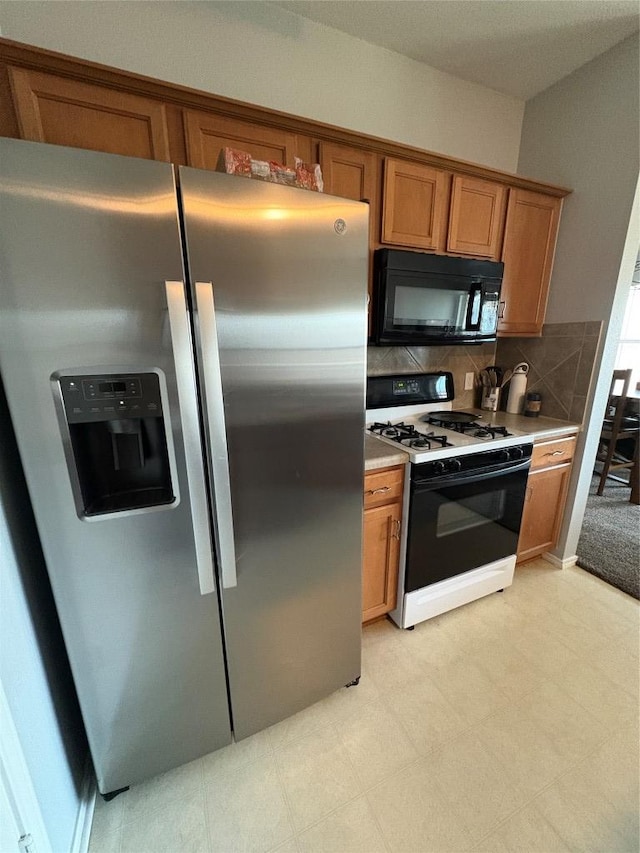 kitchen featuring brown cabinets, stainless steel refrigerator with ice dispenser, backsplash, range with gas cooktop, and black microwave