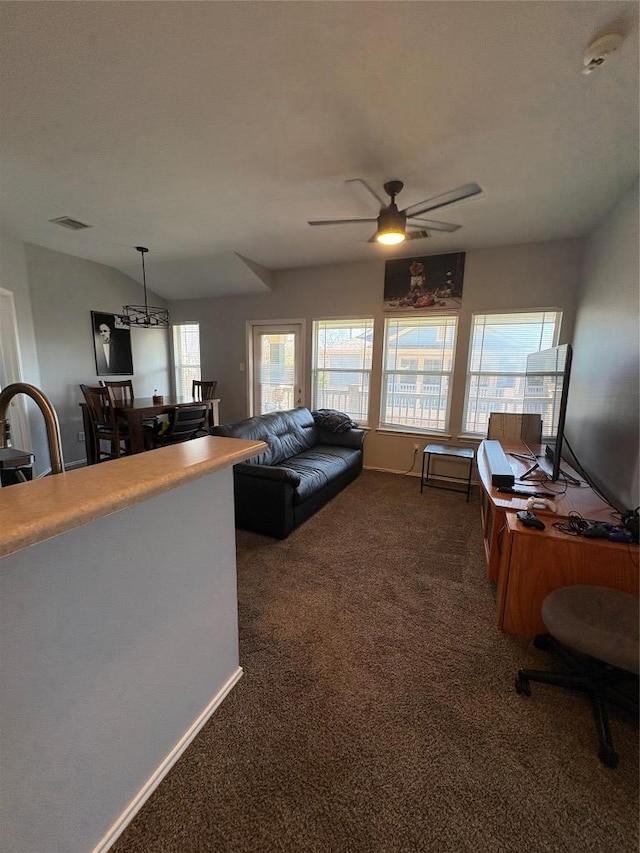 living area featuring a ceiling fan, visible vents, dark carpet, and baseboards