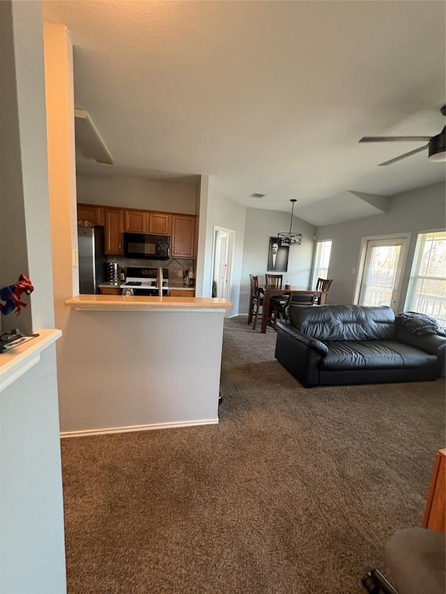 living area with baseboards, ceiling fan, and dark colored carpet