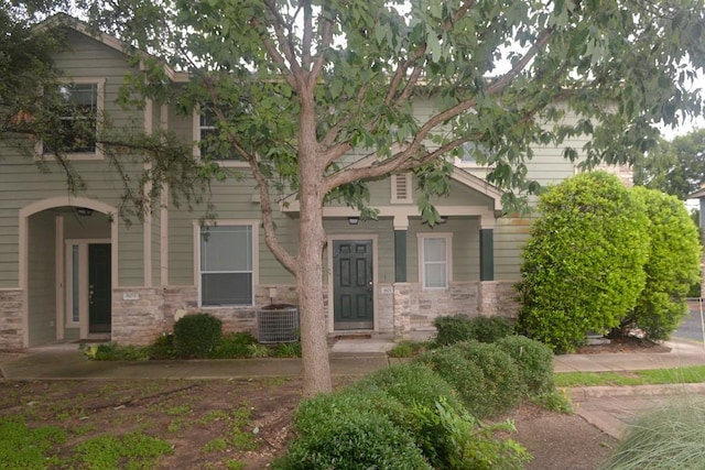 view of front facade featuring stone siding and central air condition unit