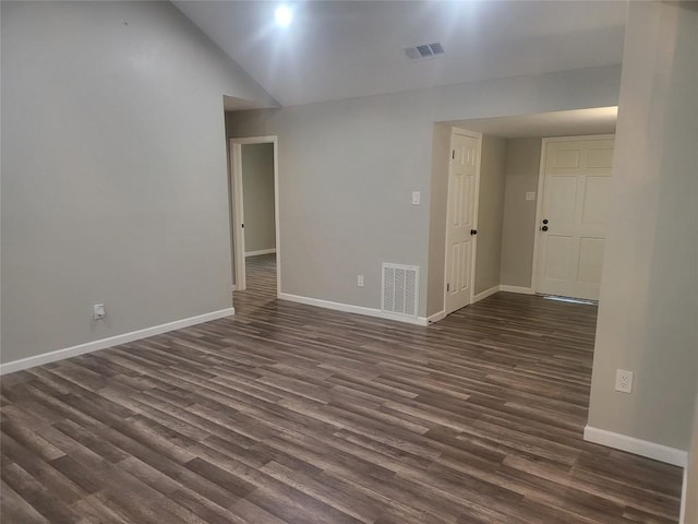 empty room with visible vents, baseboards, dark wood finished floors, and vaulted ceiling