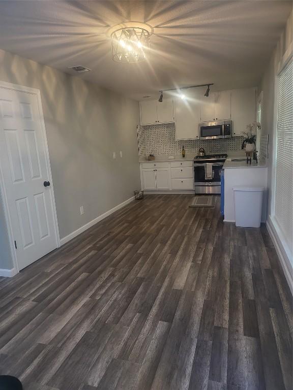 kitchen with visible vents, dark wood finished floors, light countertops, decorative backsplash, and stainless steel appliances