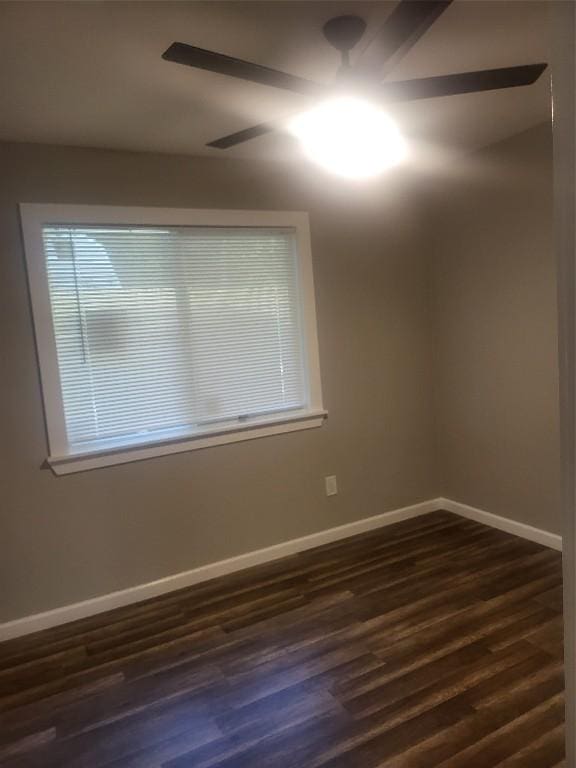 unfurnished room featuring dark wood-type flooring, a ceiling fan, and baseboards