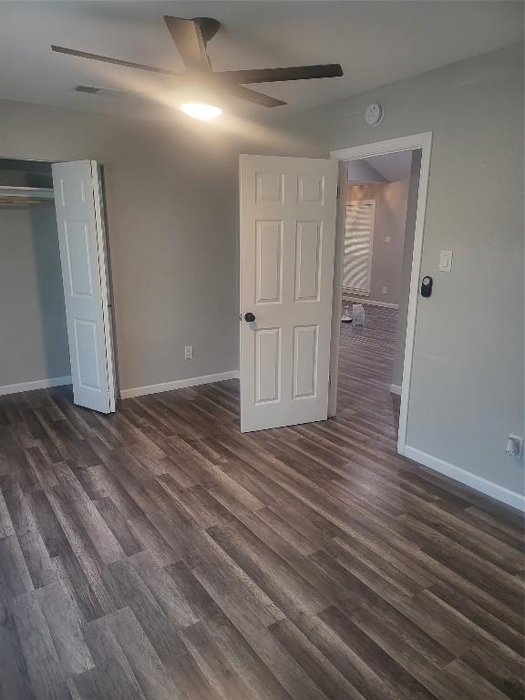 unfurnished bedroom featuring dark wood-style floors, baseboards, a closet, and ceiling fan