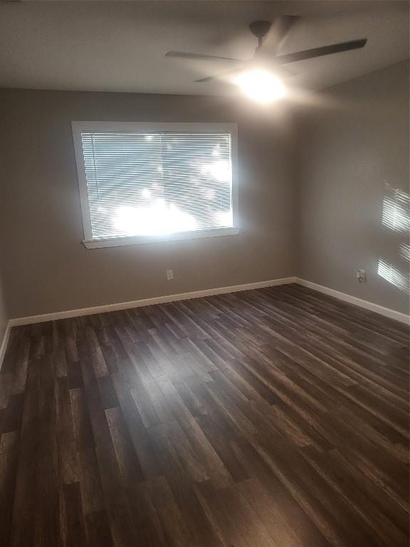 unfurnished room with baseboards and dark wood-type flooring