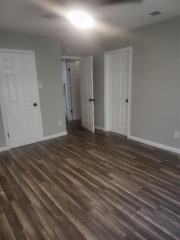 empty room with visible vents, baseboards, and dark wood-style flooring