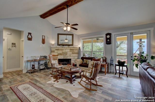 living room featuring wood finished floors, french doors, a fireplace, ceiling fan, and vaulted ceiling with beams