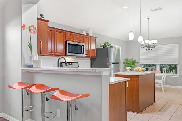 2700 Tumbling River Dr, Leander, TX 78641 - kitchen featuring stainless steel appliances, a center island, baseboards, a kitchen breakfast bar, and brown cabinetry