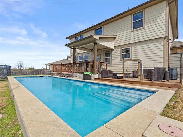 view of pool with a fenced in pool, fence, a deck, and a trampoline