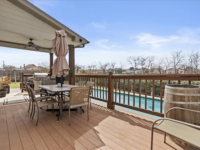 wooden terrace with an outdoor pool, outdoor dining space, and fence