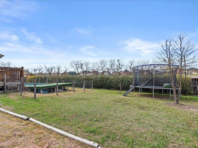 view of yard with an outdoor pool, a trampoline, and fence