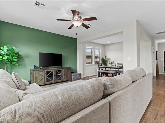 living area featuring visible vents, baseboards, wood finished floors, and an accent wall