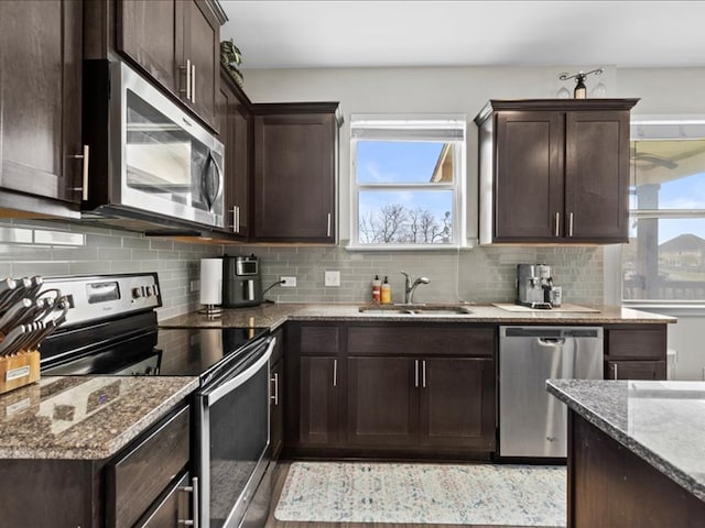 kitchen featuring a sink, decorative backsplash, dark brown cabinetry, and appliances with stainless steel finishes