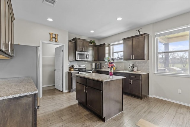 700 Carillion Dr, Pflugerville, TX 78660 - kitchen with dark brown cabinetry, backsplash, appliances with stainless steel finishes, and light wood finished floors