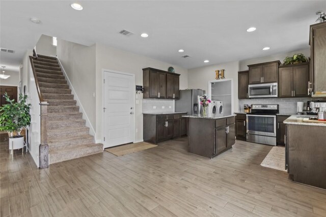 700 Carillion Dr, Pflugerville, TX 78660 - kitchen with visible vents, light wood finished floors, separate washer and dryer, dark brown cabinetry, and appliances with stainless steel finishes