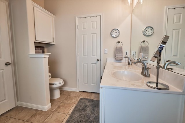 bathroom featuring tile patterned floors, double vanity, toilet, and a sink