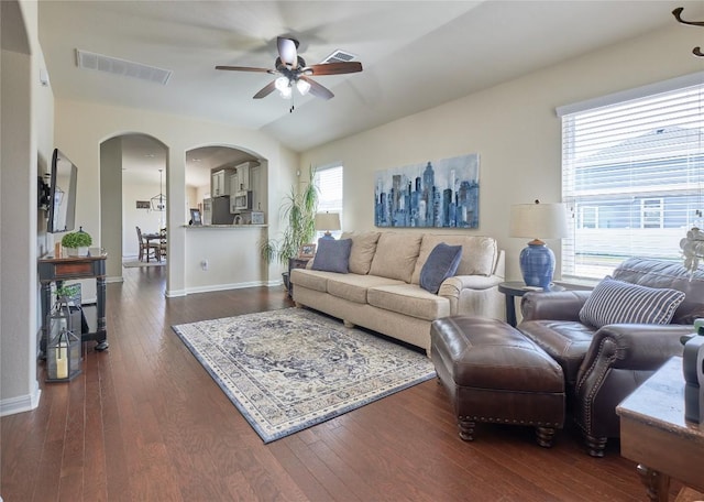 living room featuring arched walkways, visible vents, plenty of natural light, and dark wood-style flooring