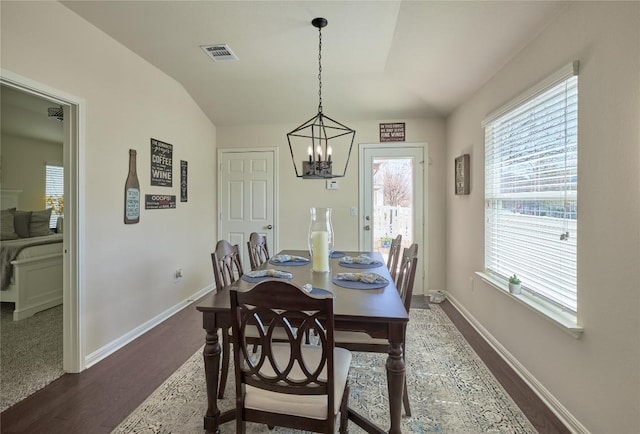 dining area with visible vents, baseboards, vaulted ceiling, dark wood-type flooring, and a chandelier