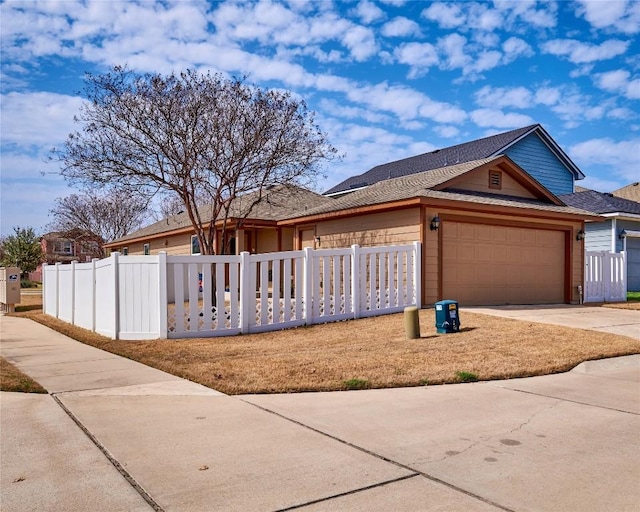 view of front of property featuring a fenced front yard, an attached garage, and driveway