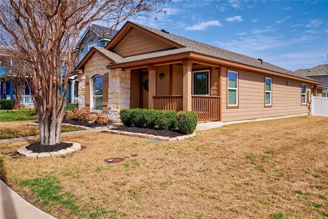 view of front of house featuring stone siding, covered porch, and a front yard