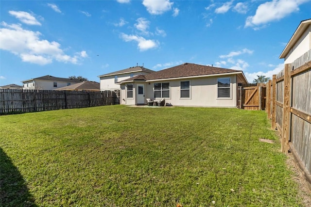 rear view of house with a lawn and a fenced backyard