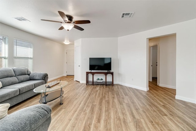 living room featuring light wood-type flooring, visible vents, baseboards, and ceiling fan