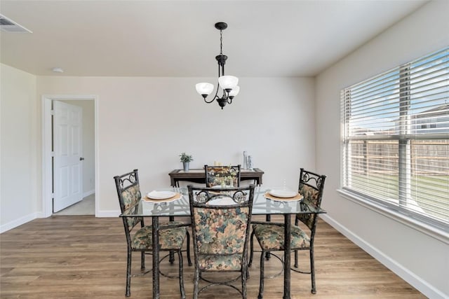 dining space featuring baseboards, a chandelier, and light wood finished floors