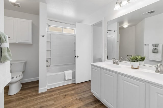 full bath featuring toilet, wood finished floors, visible vents, and a sink