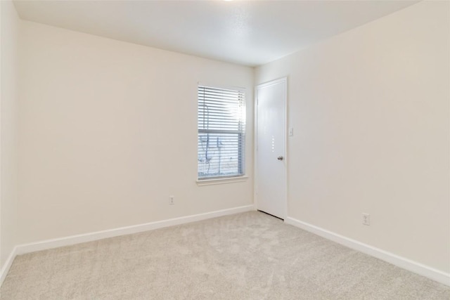 spare room featuring light carpet and baseboards