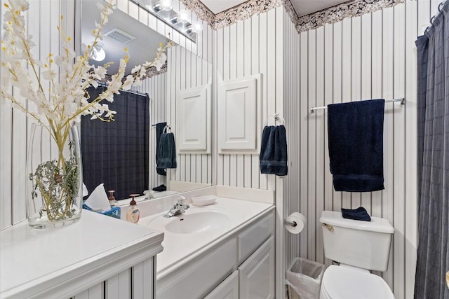 bathroom with visible vents, toilet, vanity, and wallpapered walls