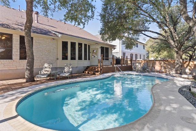 view of swimming pool with a fenced in pool, a wooden deck, and a patio