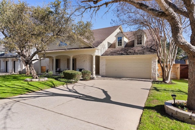 view of front of property featuring stone siding, an attached garage, driveway, and a front yard