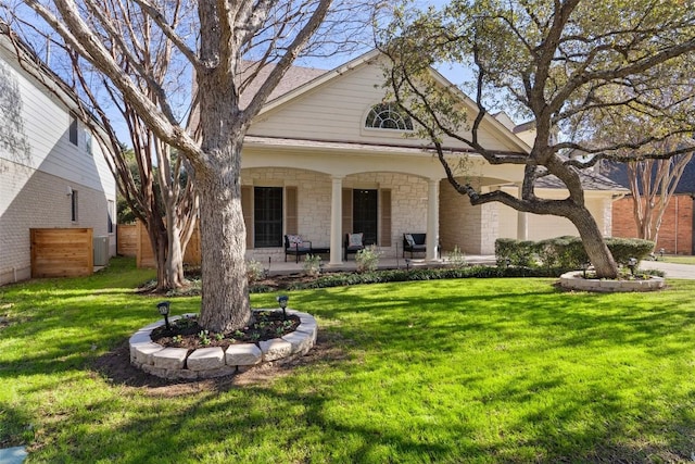 view of front of property featuring stone siding, covered porch, and a front yard