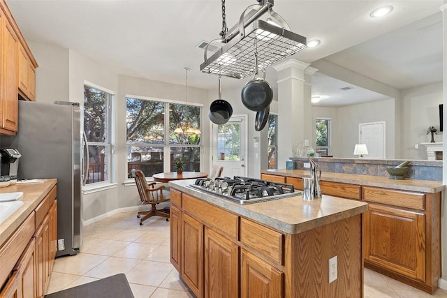 kitchen featuring light tile patterned floors, brown cabinetry, appliances with stainless steel finishes, and a center island