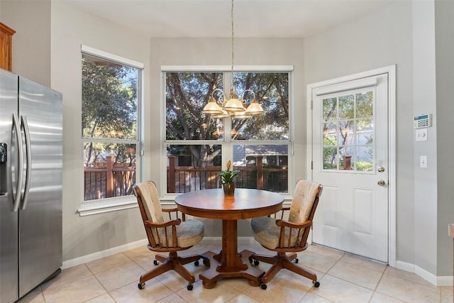 dining space featuring light tile patterned floors, baseboards, plenty of natural light, and a chandelier