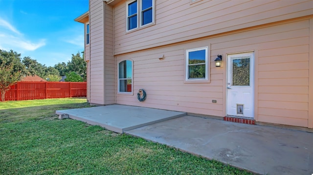 rear view of property featuring a lawn, a patio, and fence