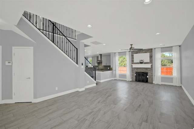 unfurnished living room with visible vents, baseboards, stairs, a stone fireplace, and recessed lighting