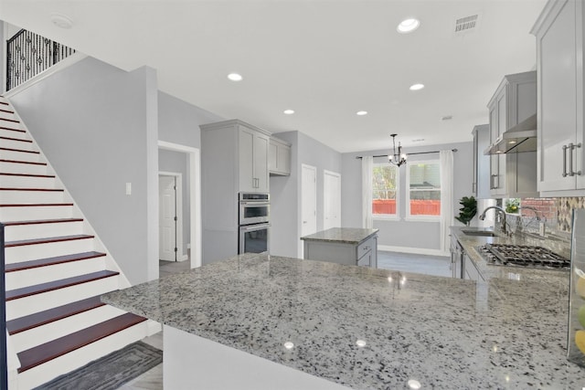 kitchen featuring light stone countertops, visible vents, a sink, appliances with stainless steel finishes, and a center island