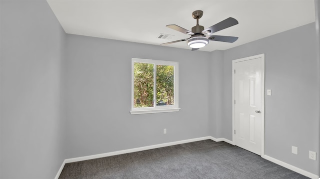 unfurnished room with visible vents, dark carpet, a ceiling fan, and baseboards