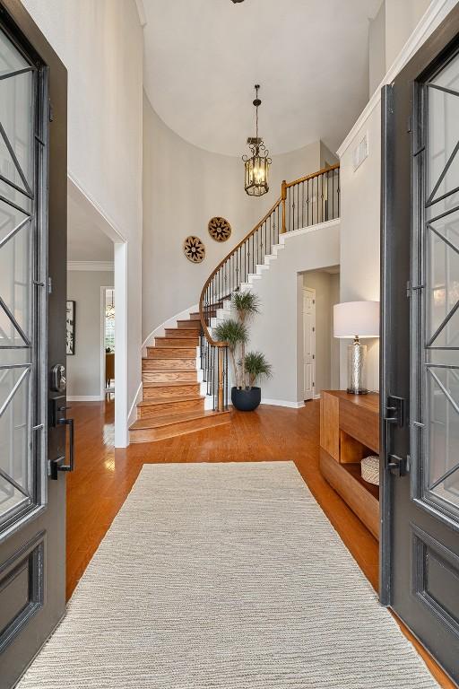 foyer featuring stairway, a high ceiling, baseboards, and wood finished floors