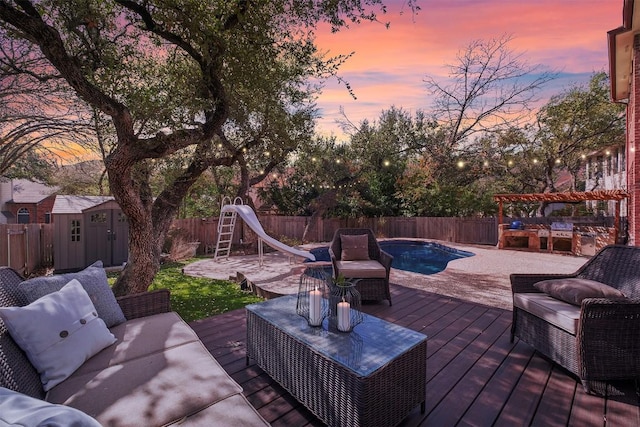 deck at dusk featuring an outdoor living space, a fenced backyard, a storage shed, an outdoor structure, and a fenced in pool