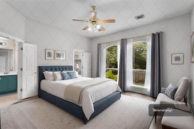 bedroom with a ceiling fan, visible vents, light tile patterned flooring, a sink, and connected bathroom