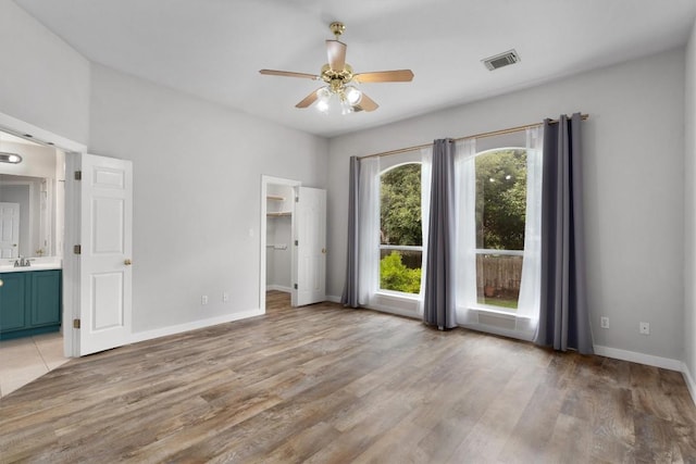 709 Stevenage Dr, Pflugerville, TX 78660 - unfurnished bedroom with light wood-style floors, connected bathroom, a spacious closet, and a ceiling fan